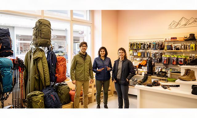 Beratungsteam von Tanner Outdoor im hellen Outdoor-Ladengeschäft in Bernex zwischen Rucksäcken und Wanderausrüstung